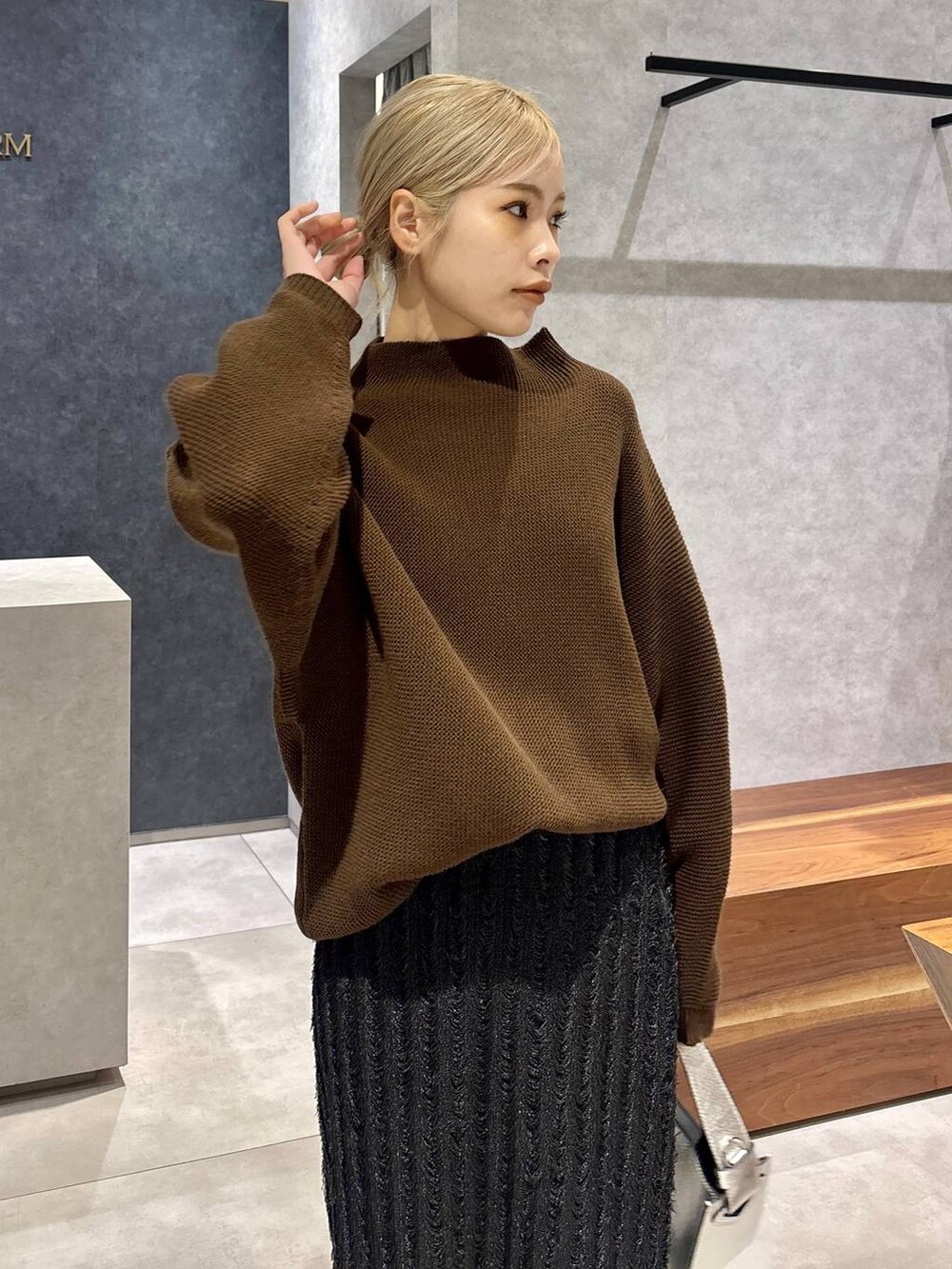 シルバー系のハンドバッグ、シルバー系のローファー、ブラック系のスカートを着用したレディースの冬コーディネートの3枚目の写真