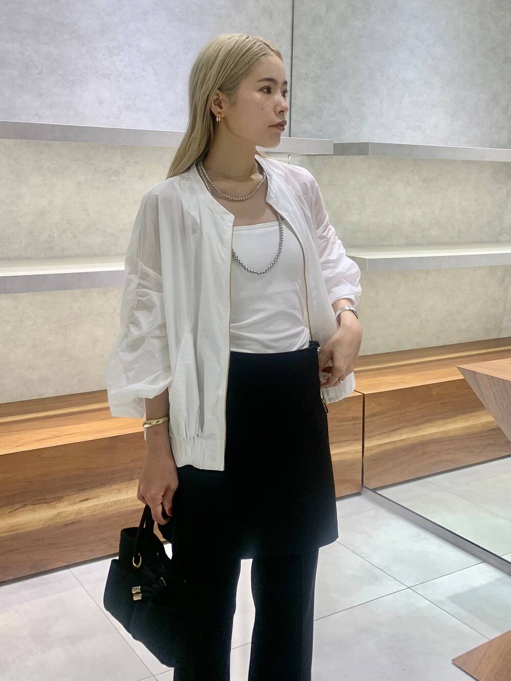ブラック系のセットアップ、ホワイト系のブルゾン、ブラック系のパンプスを着用したレディースの夏コーディネートの5枚目の写真