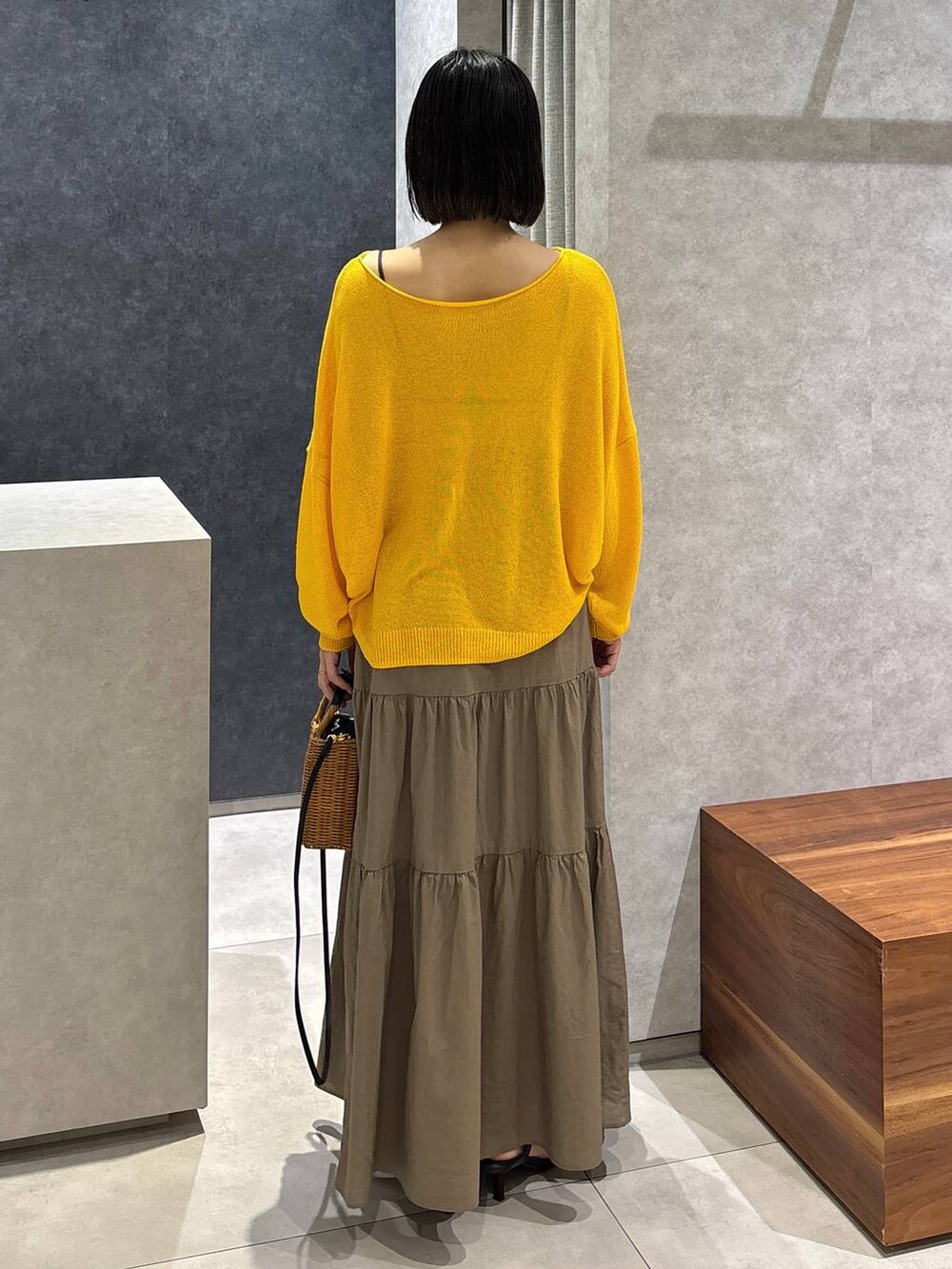 ブラック系のショルダーバッグ、ブラック系のサンダル、イエロー系のニット/セーターを着用したレディースの夏コーディネートの3枚目の写真