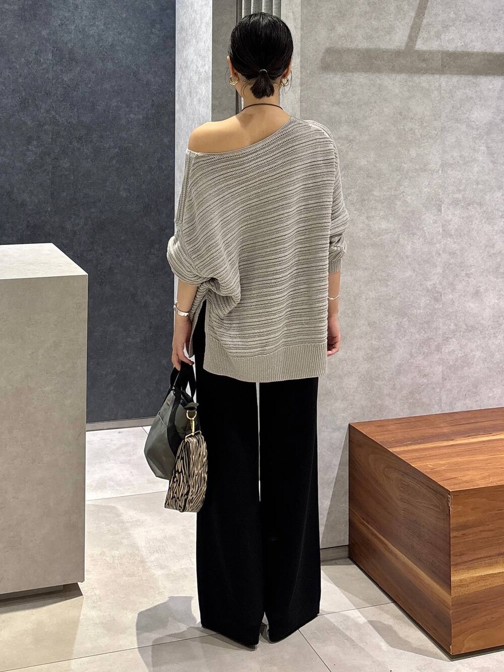 グレー系のニット/セーター、グレー系のトートバッグ、ブラック系のサンダルを着用したレディースの夏コーディネートの2枚目の写真