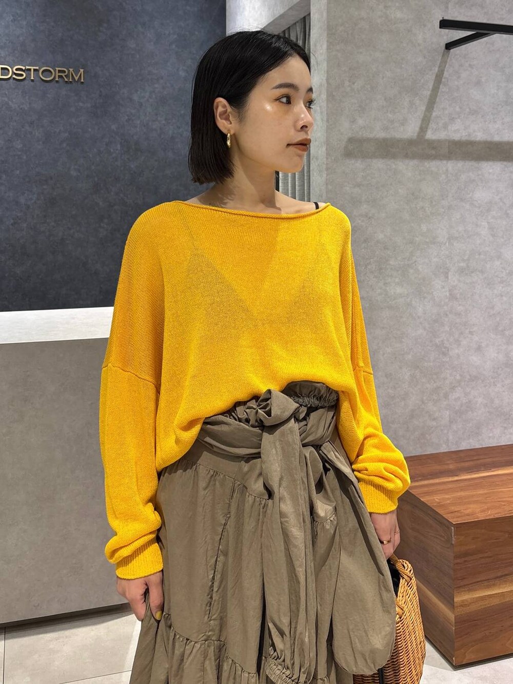 ブラック系のショルダーバッグ、ブラック系のサンダル、イエロー系のニット/セーターを着用したレディースの夏コーディネートの7枚目の写真