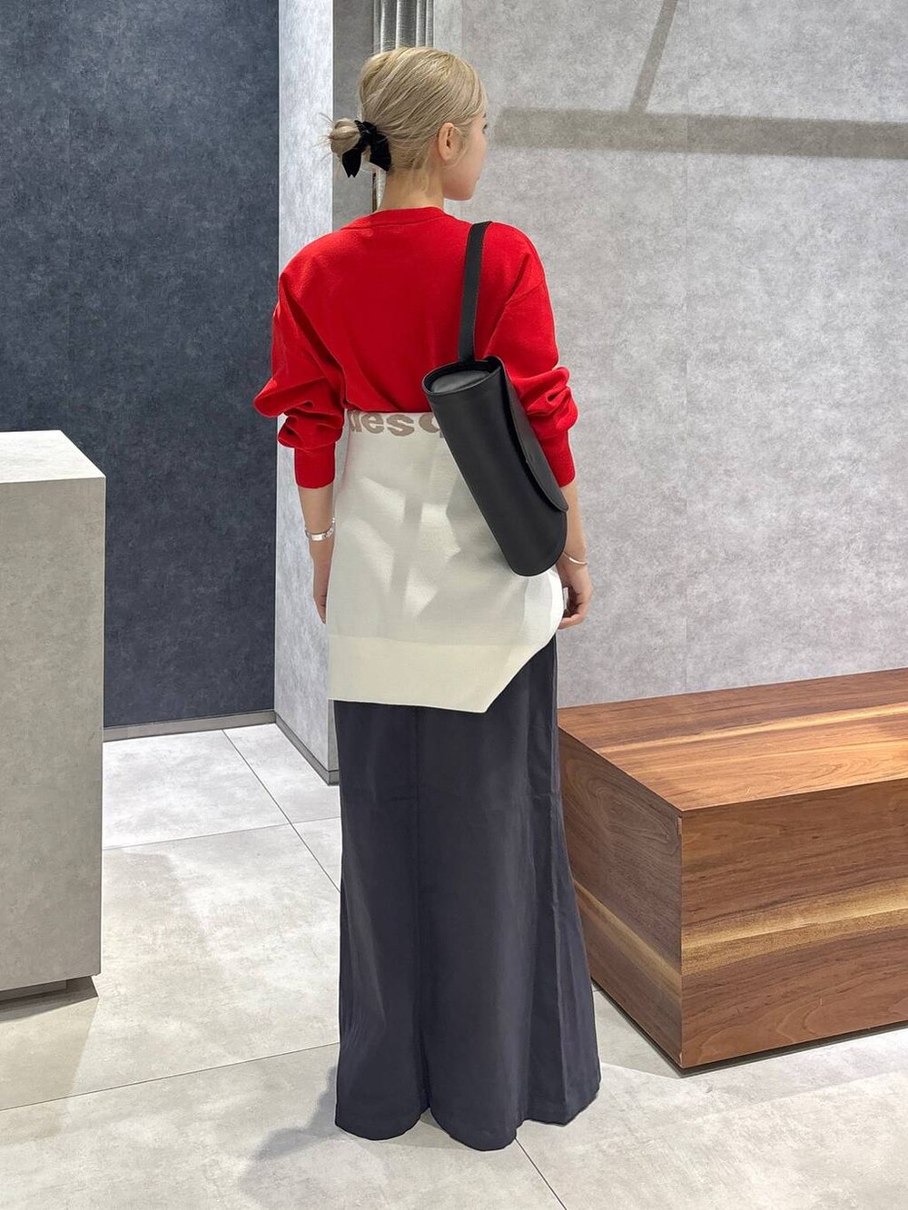 グレー系のスカート、レッド系のニット/セーター、ホワイト系のスニーカーを着用したレディースの冬コーディネートの2枚目の写真