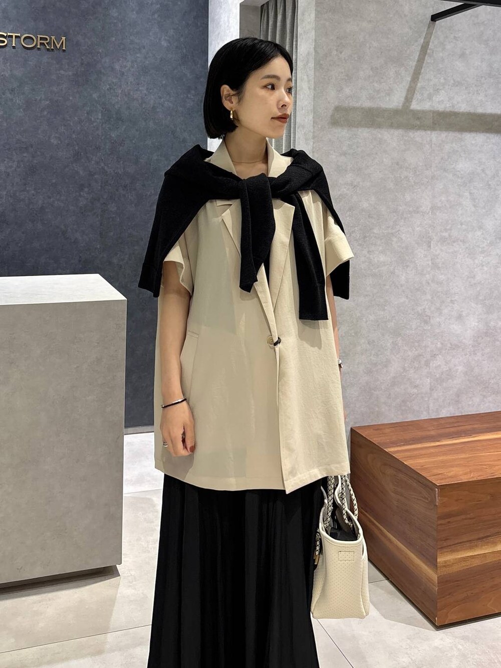 ブラック系のトートバッグ、ベージュ系のテーラードジャケット、ブラック系のサンダルを着用したレディースの春コーディネートの4枚目の写真