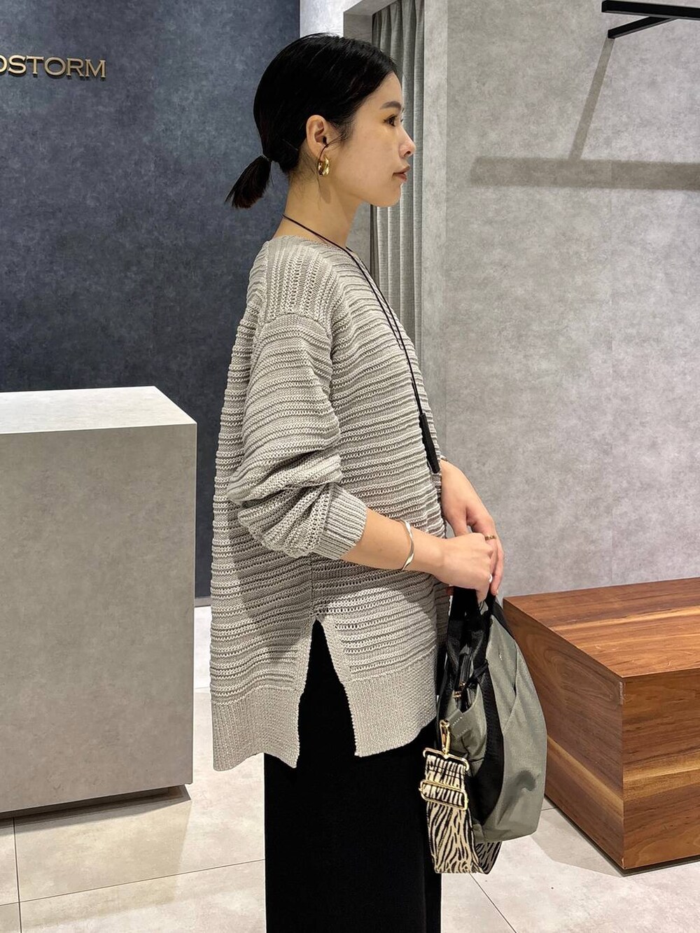 グレー系のニット/セーター、グレー系のトートバッグ、ブラック系のサンダルを着用したレディースの夏コーディネートの4枚目の写真