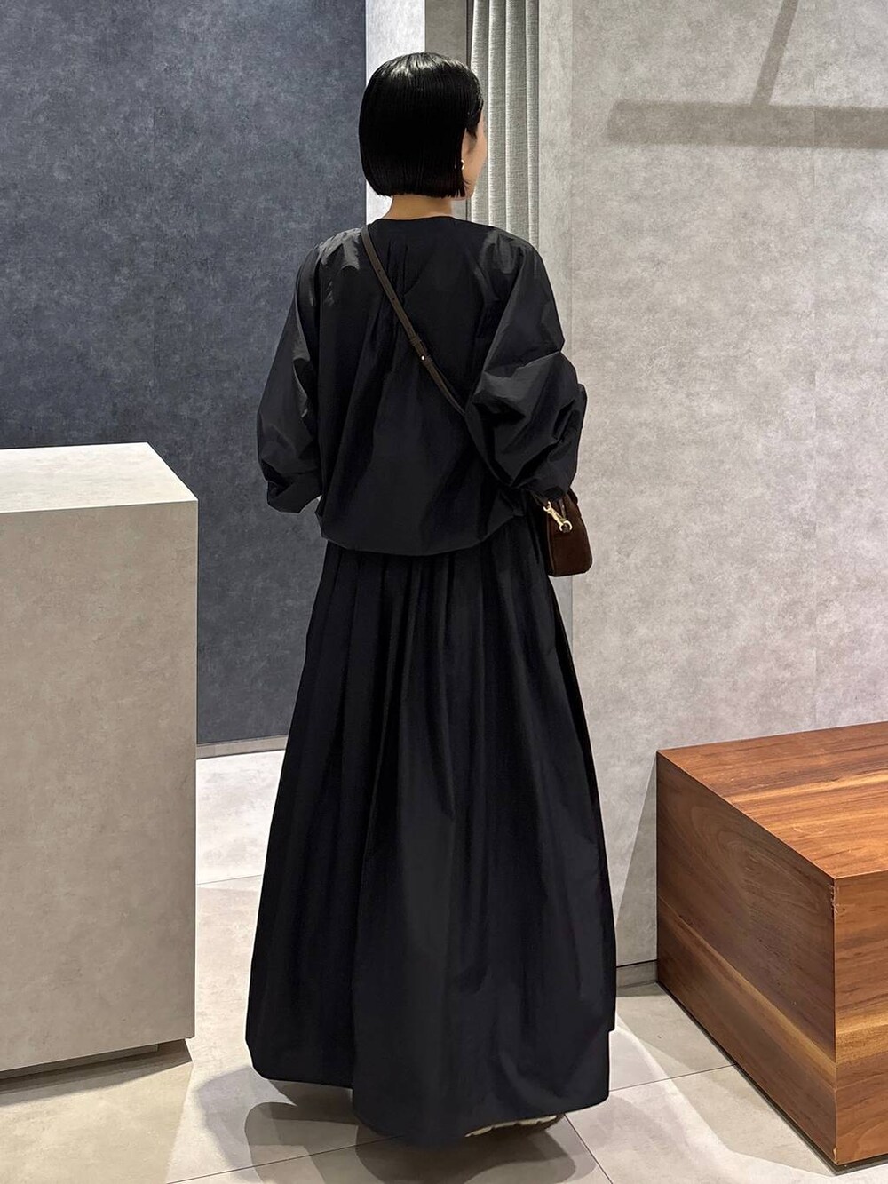 ブラック系のスカート、ブラック系のブルゾン、ブラウン系のショルダーバッグを着用したレディースの夏コーディネートの3枚目の写真