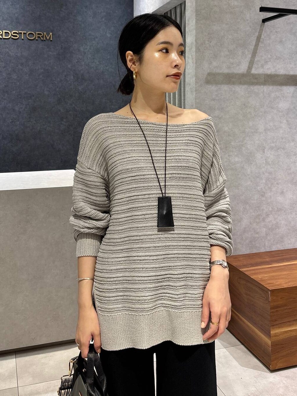 グレー系のニット/セーター、グレー系のトートバッグ、ブラック系のサンダルを着用したレディースの夏コーディネートの3枚目の写真