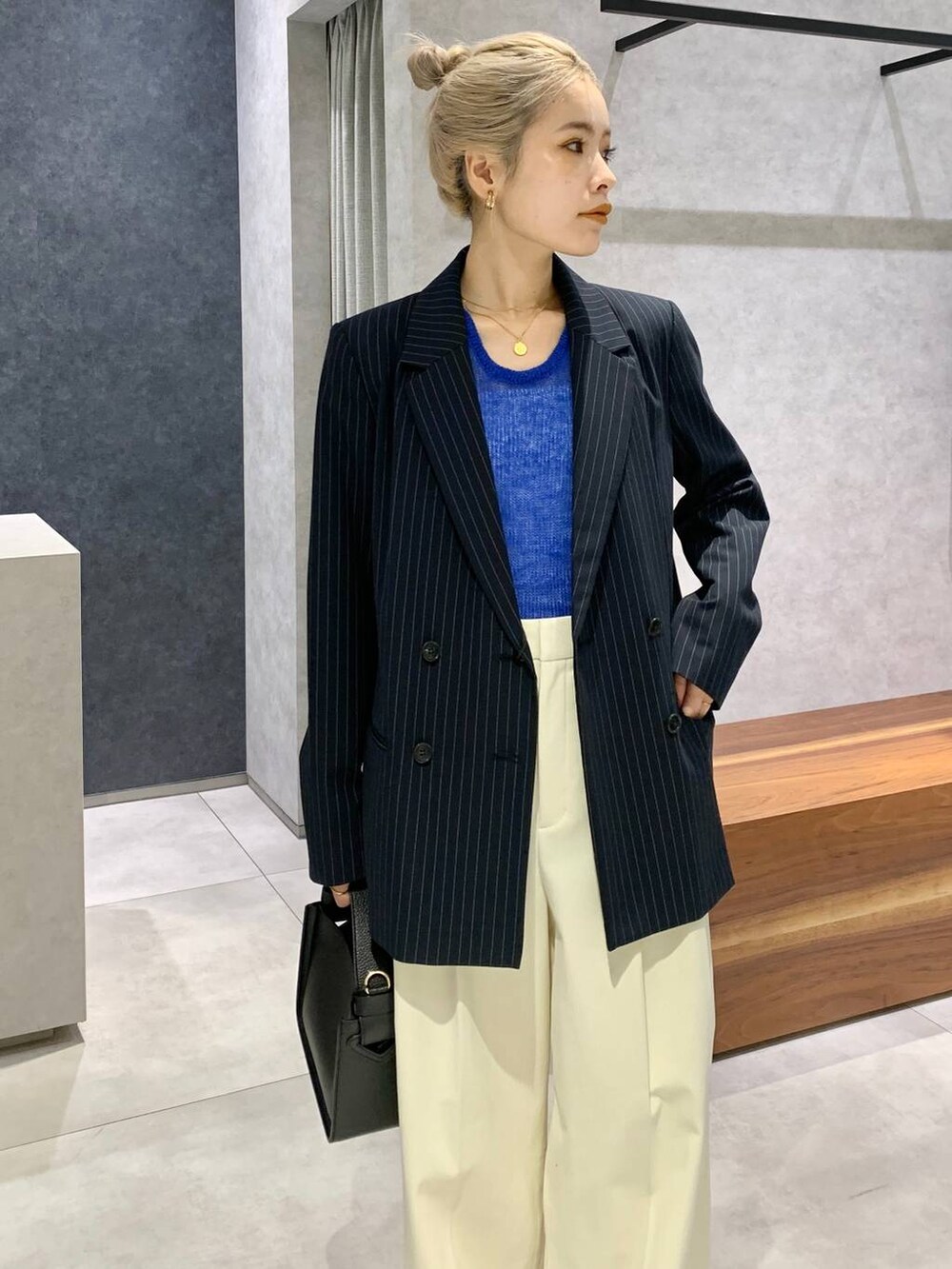 ブラック系のハンドバッグ、シルバー系のパンプス、ブルー系のニット/セーターを着用したレディースの秋コーディネートの4枚目の写真