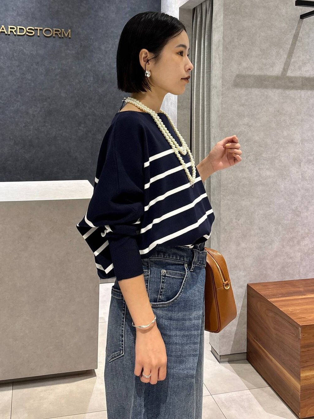 ブルー系のデニムパンツ、イエロー系のハンドバッグ、ブルー系のニット/セーターを着用したレディースの夏コーディネートの5枚目の写真