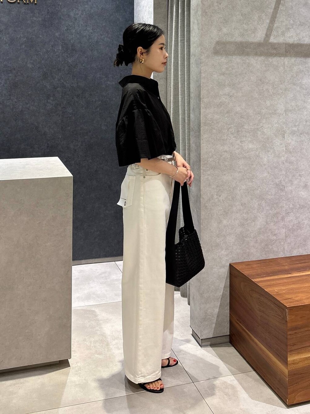 ホワイト系のデニムパンツ、ブラック系のサンダル、ブラック系のハンドバッグを着用したレディースの夏コーディネートの2枚目の写真