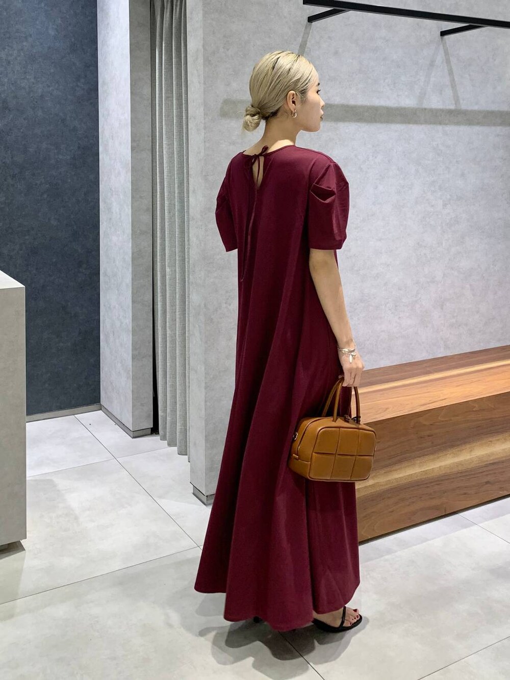 ブラック系のスリッポン、ブラウン系のハンドバッグ、レッド系のワンピースを着用したレディースの夏コーディネートの2枚目の写真