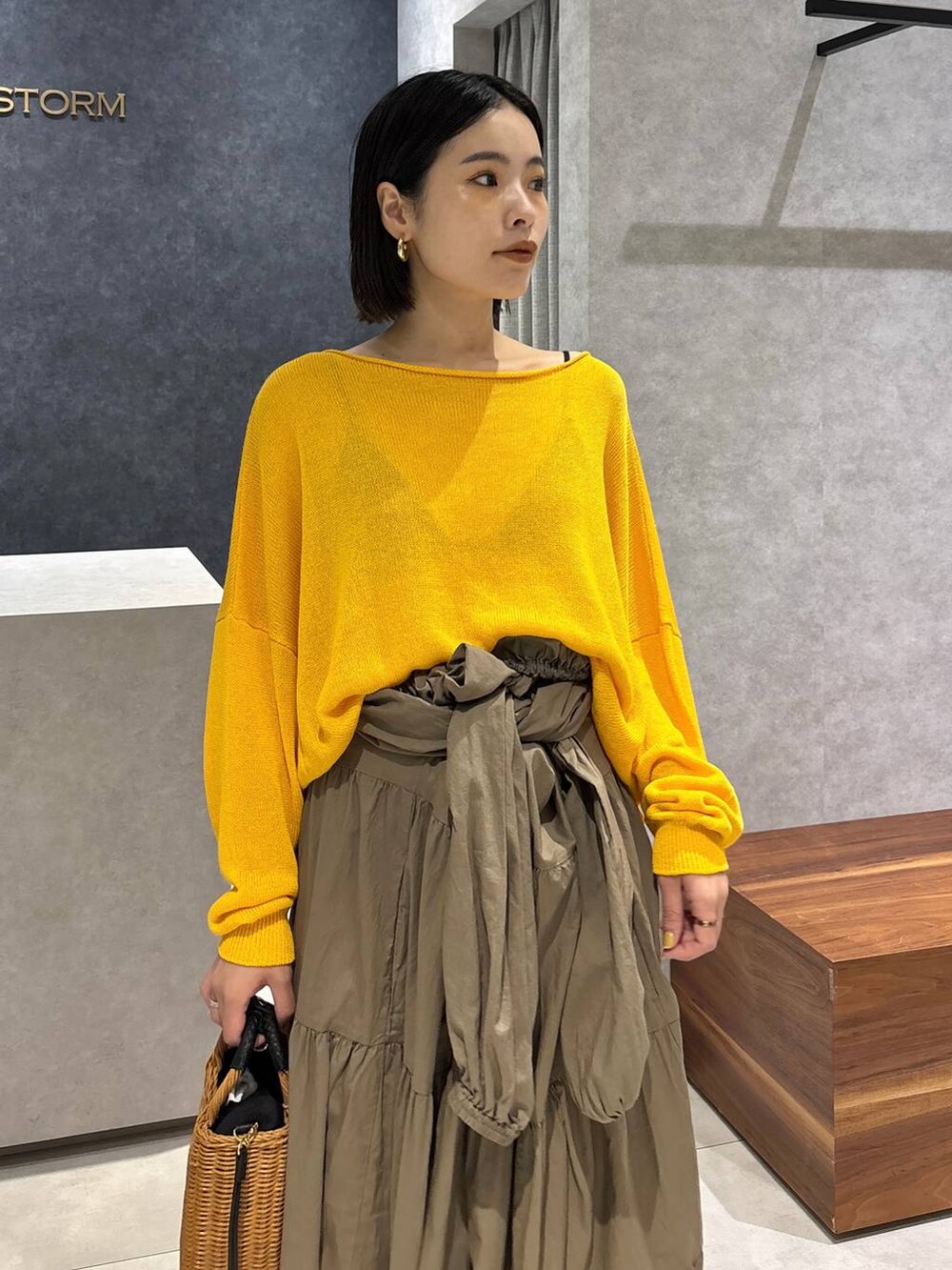 ブラック系のショルダーバッグ、ブラック系のサンダル、イエロー系のニット/セーターを着用したレディースの夏コーディネートの4枚目の写真