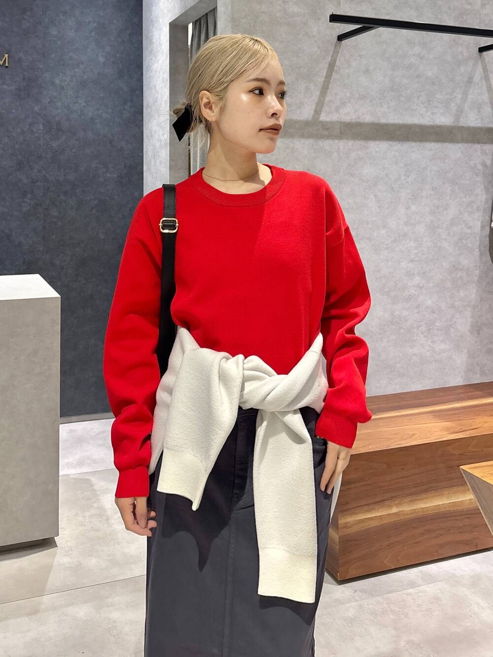 グレー系のスカート、レッド系のニット/セーター、ホワイト系のスニーカーを着用したレディースの冬コーディネートの3枚目の写真