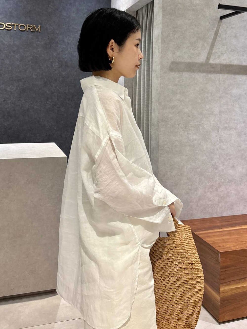 ブラウン系のトートバッグ、ブラック系のサンダル、ホワイト系のシャツ/ブラウスを着用したレディースの春コーディネートの6枚目の写真