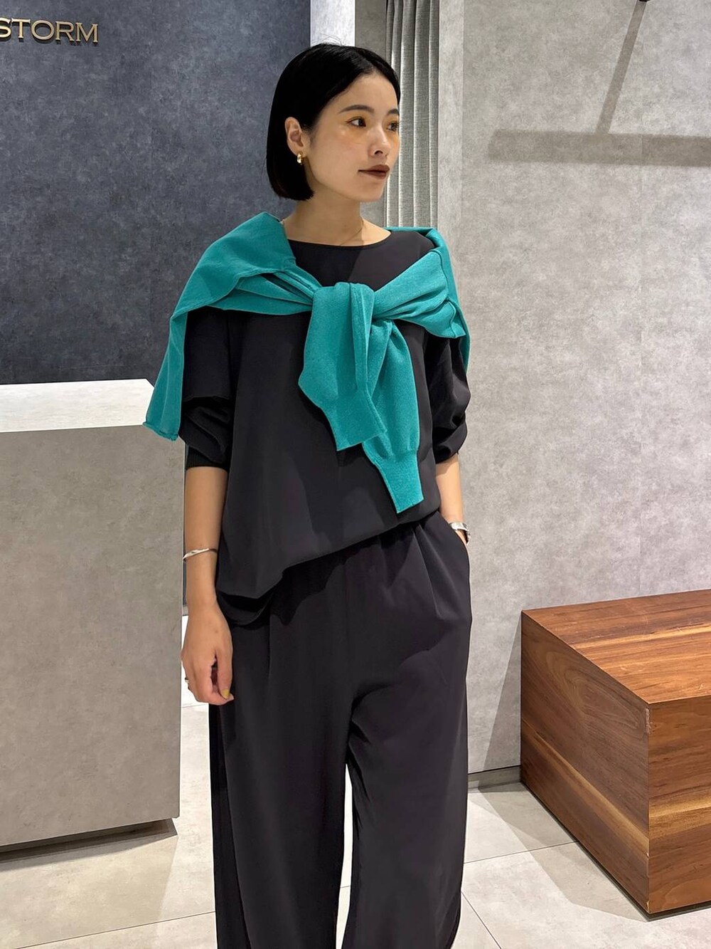 グレー系のシャツ/ブラウス、グレー系のスラックス、グリーン系のニット/セーターを着用したレディースの夏コーディネートの9枚目の写真