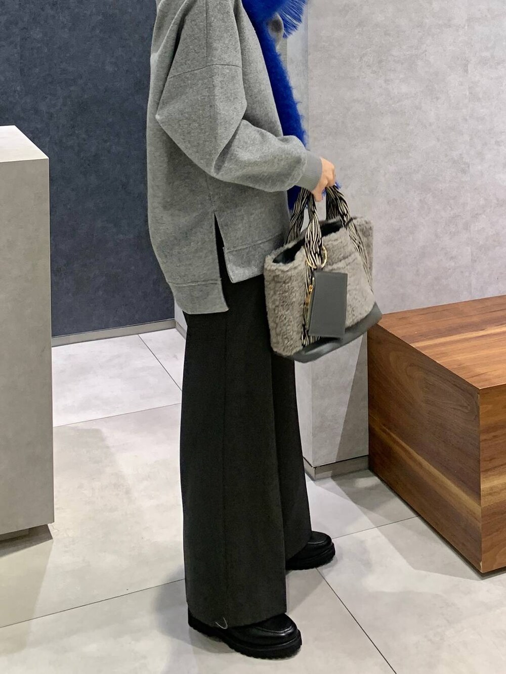 グレー系のパーカー、グレー系のトートバッグ、ブラック系のローファーを着用したレディースの秋コーディネートの2枚目の写真