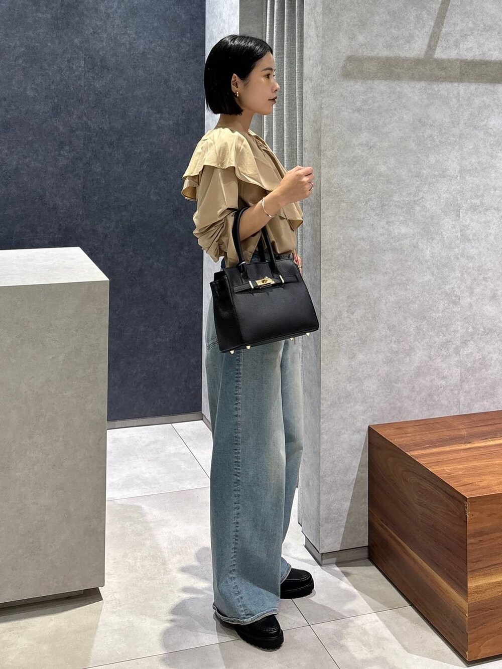 ブルー系のデニムパンツ、ブラック系のローファー、ブラック系のショルダーバッグを着用したレディースの夏コーディネートの2枚目の写真