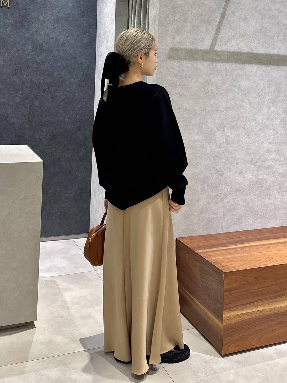 イエロー系のボストンバッグ、ブラック系のローファー、ブラック系のニット/セーターを着用したレディースの冬コーディネートの3枚目の写真