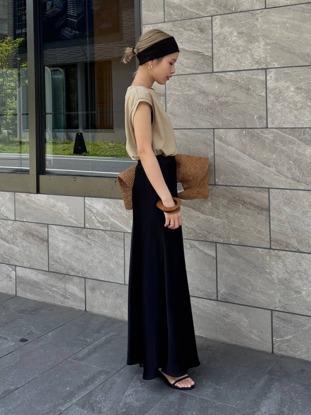 ブラウン系のトートバッグ、ベージュ系のTシャツ/カットソー、ブラック系のスカートを着用したレディースの春コーディネートの3枚目の写真