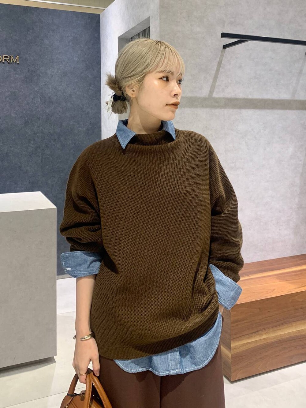 ブルー系のシャツ/ブラウス、イエロー系のボストンバッグ、ブラウン系のスウェットパンツを着用したレディースの冬コーディネートの2枚目の写真