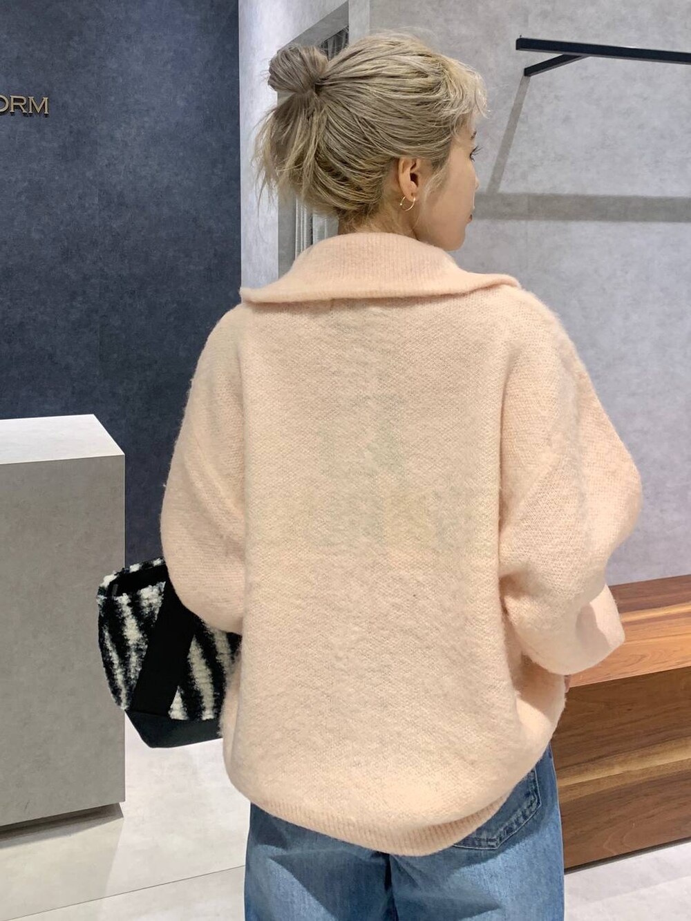 ブルー系のデニムパンツ、ホワイト系のトートバッグ、ピンク系のカーディガン/ボレロを着用したレディースの冬コーディネートの5枚目の写真