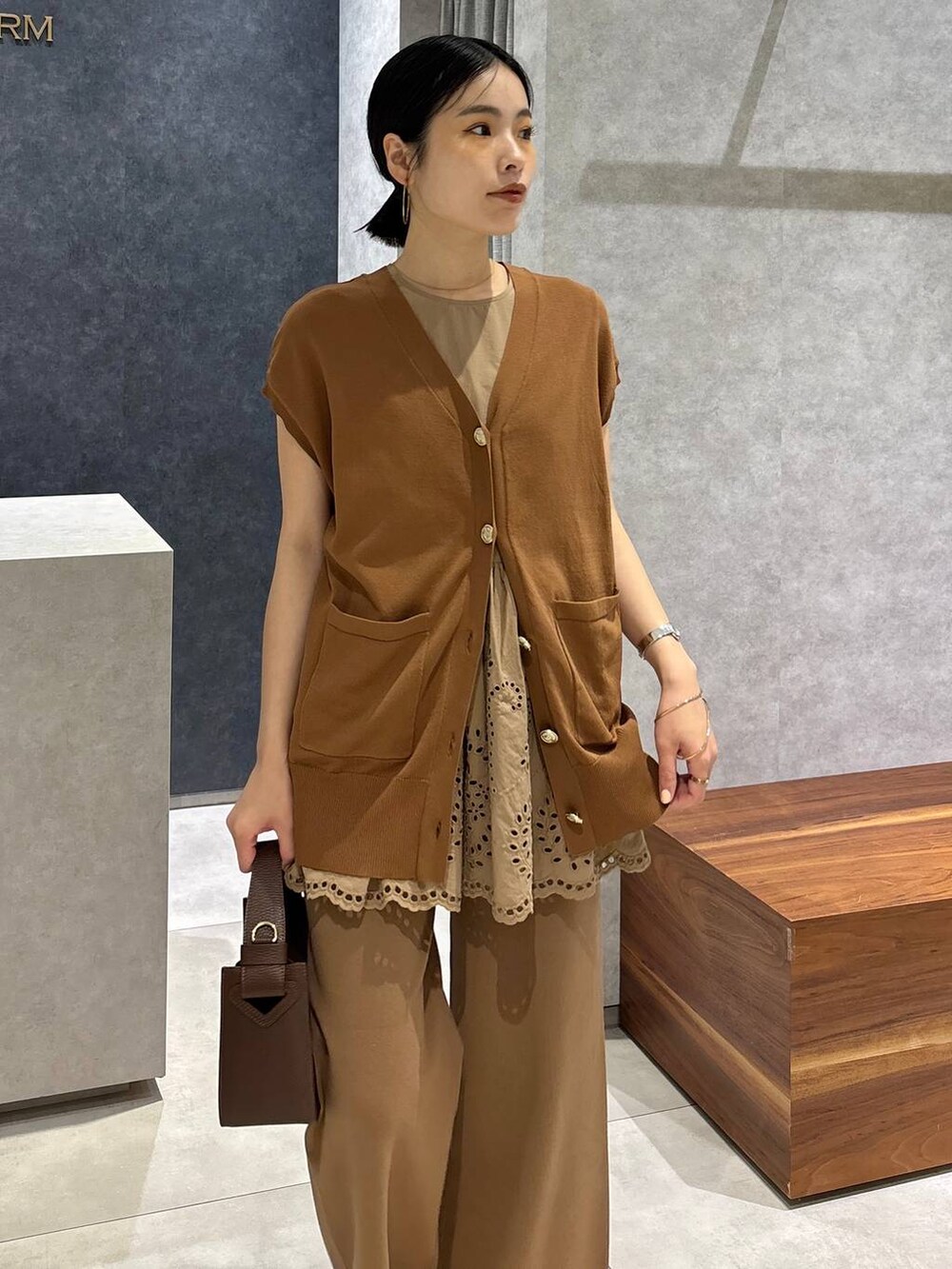 ブラウン系のハンドバッグ、ブラック系のサンダル、イエロー系のニット/セーターを着用したレディースの夏コーディネートの4枚目の写真