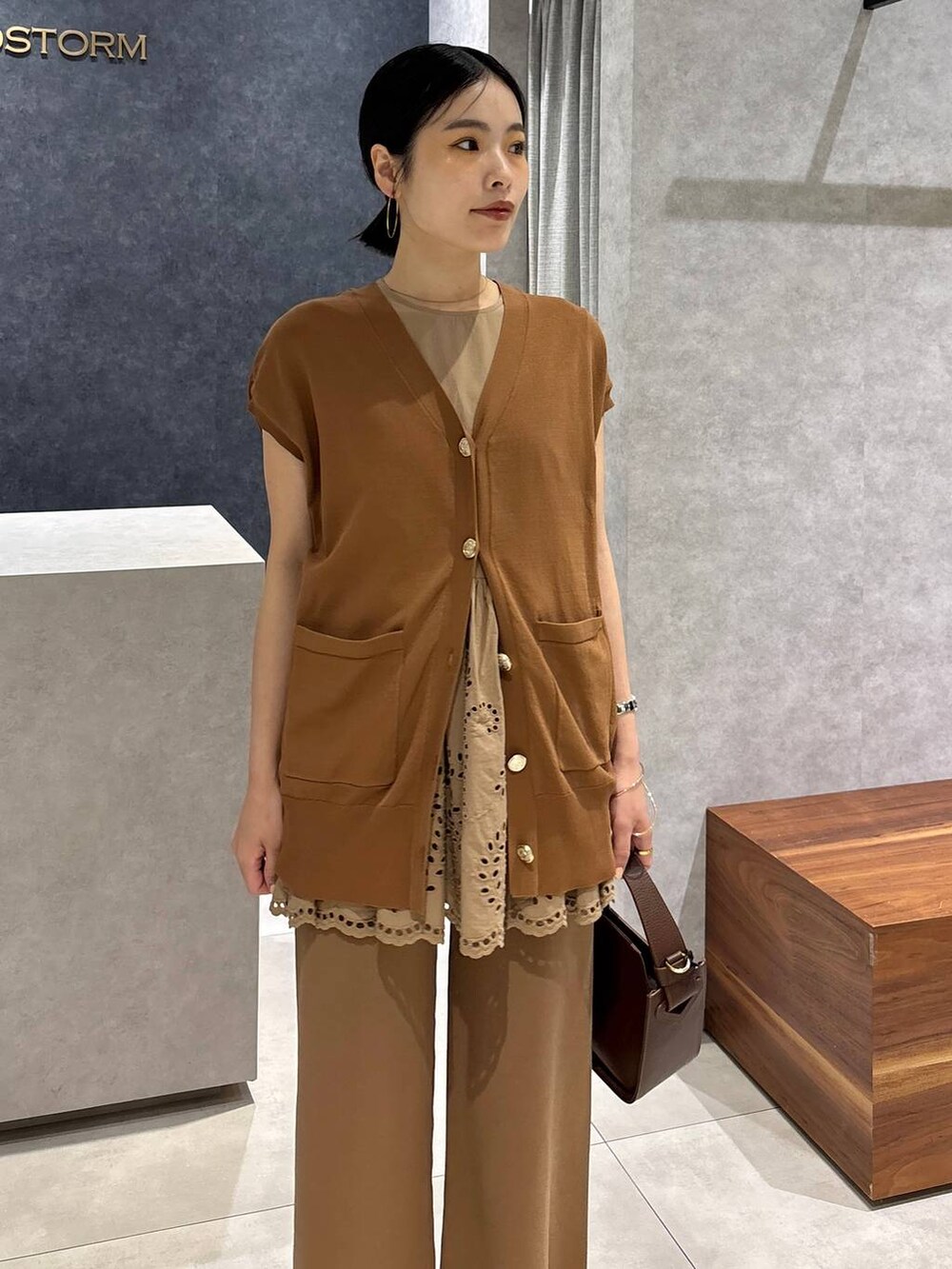 ブラウン系のハンドバッグ、ブラック系のサンダル、イエロー系のニット/セーターを着用したレディースの夏コーディネートの5枚目の写真