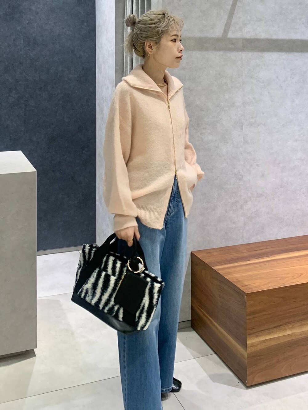 ブルー系のデニムパンツ、ホワイト系のトートバッグ、ピンク系のカーディガン/ボレロを着用したレディースの冬コーディネートの2枚目の写真
