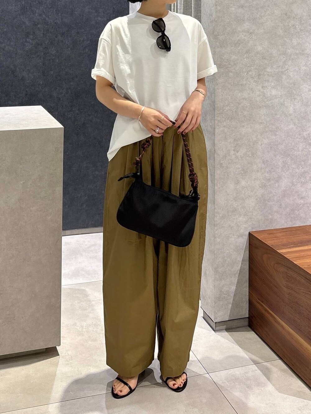 ベージュ系のその他パンツ、ブラック系のサンダル、ホワイト系のTシャツ/カットソーを着用したレディースの春コーディネートの5枚目の写真