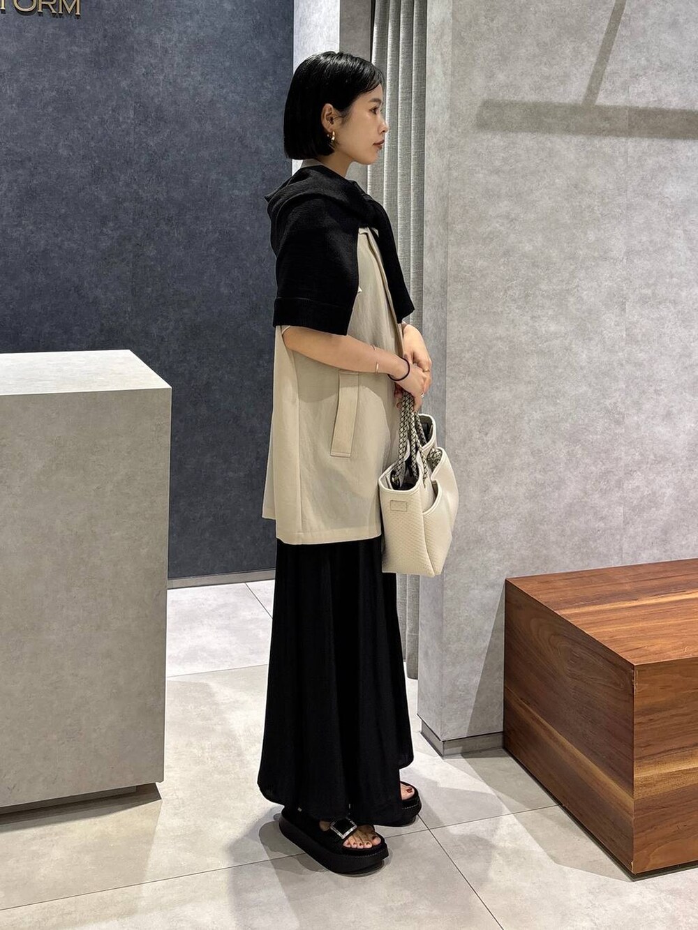 ブラック系のトートバッグ、ベージュ系のテーラードジャケット、ブラック系のサンダルを着用したレディースの春コーディネートの2枚目の写真