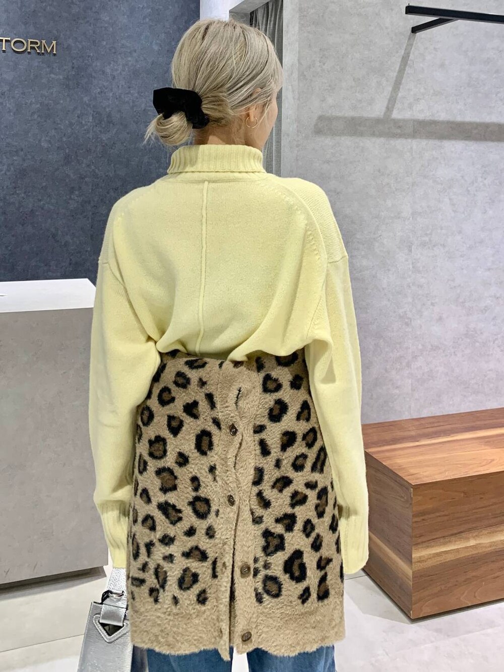 シルバー系のハンドバッグ、ブルー系のデニムパンツ、イエロー系のニット/セーターを着用したレディースの冬コーディネートの3枚目の写真