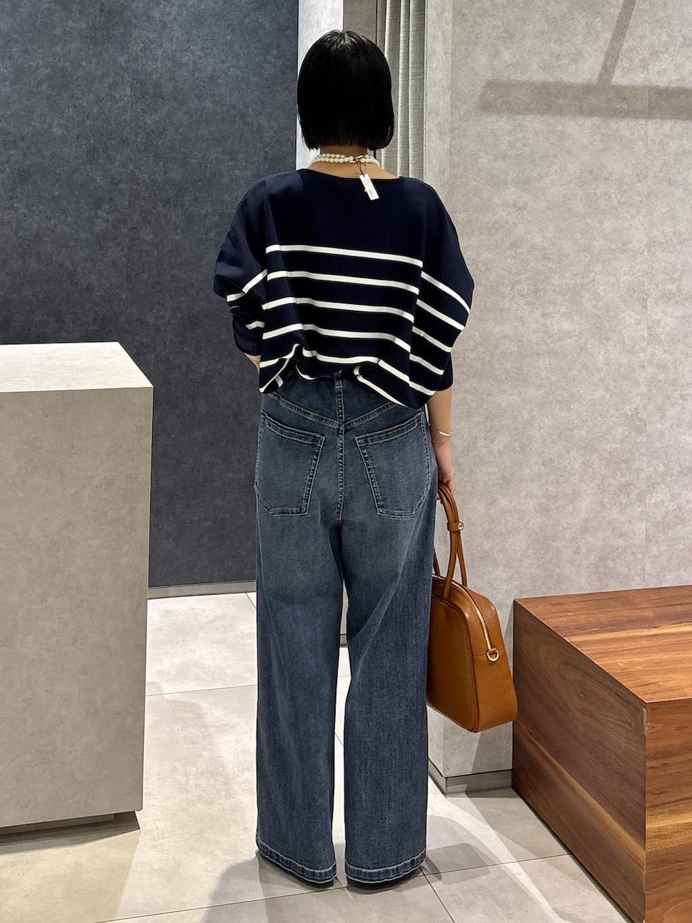 ブルー系のデニムパンツ、イエロー系のハンドバッグ、ブルー系のニット/セーターを着用したレディースの夏コーディネートの3枚目の写真