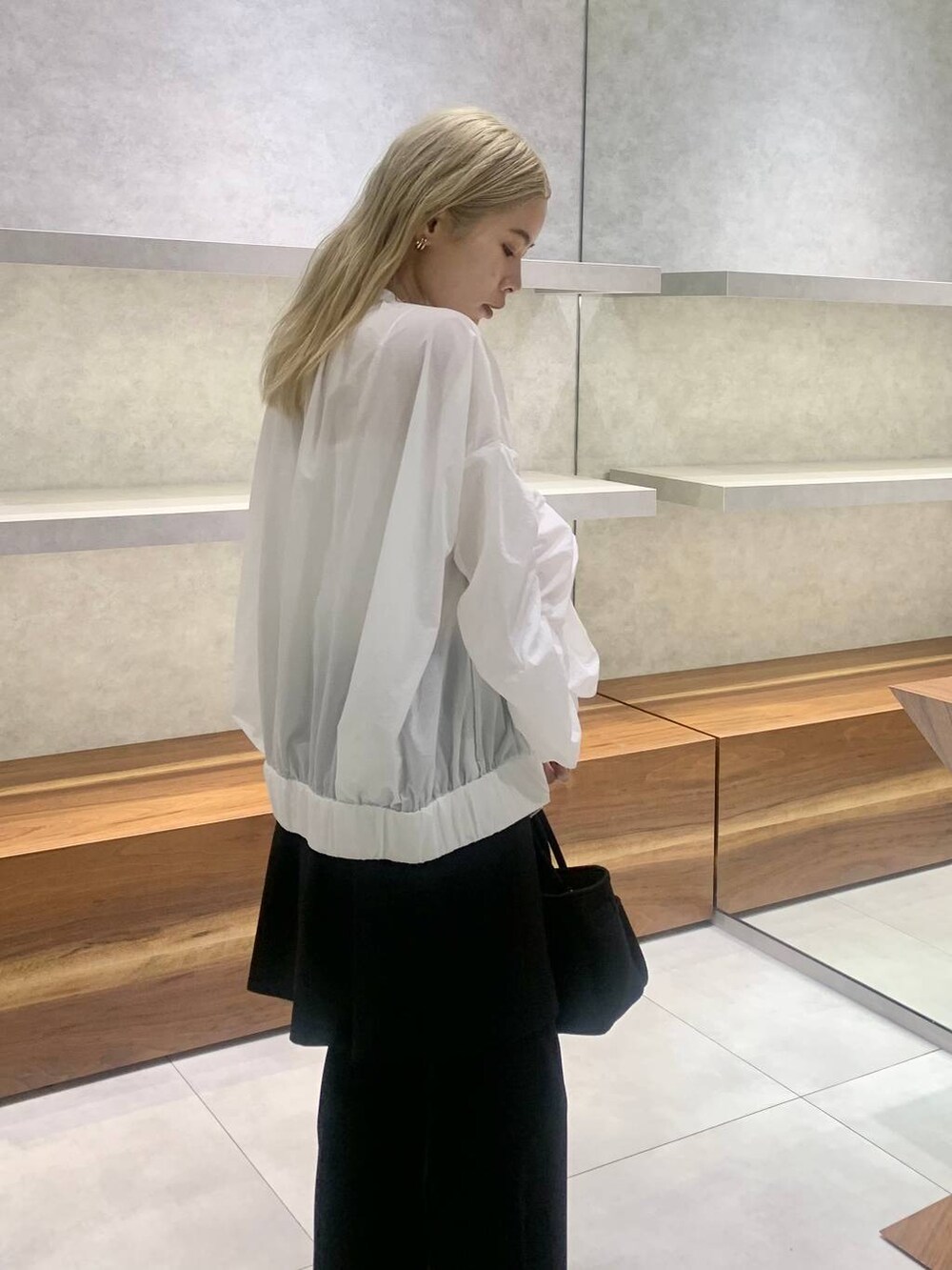 ブラック系のセットアップ、ホワイト系のブルゾン、ブラック系のパンプスを着用したレディースの夏コーディネートの4枚目の写真