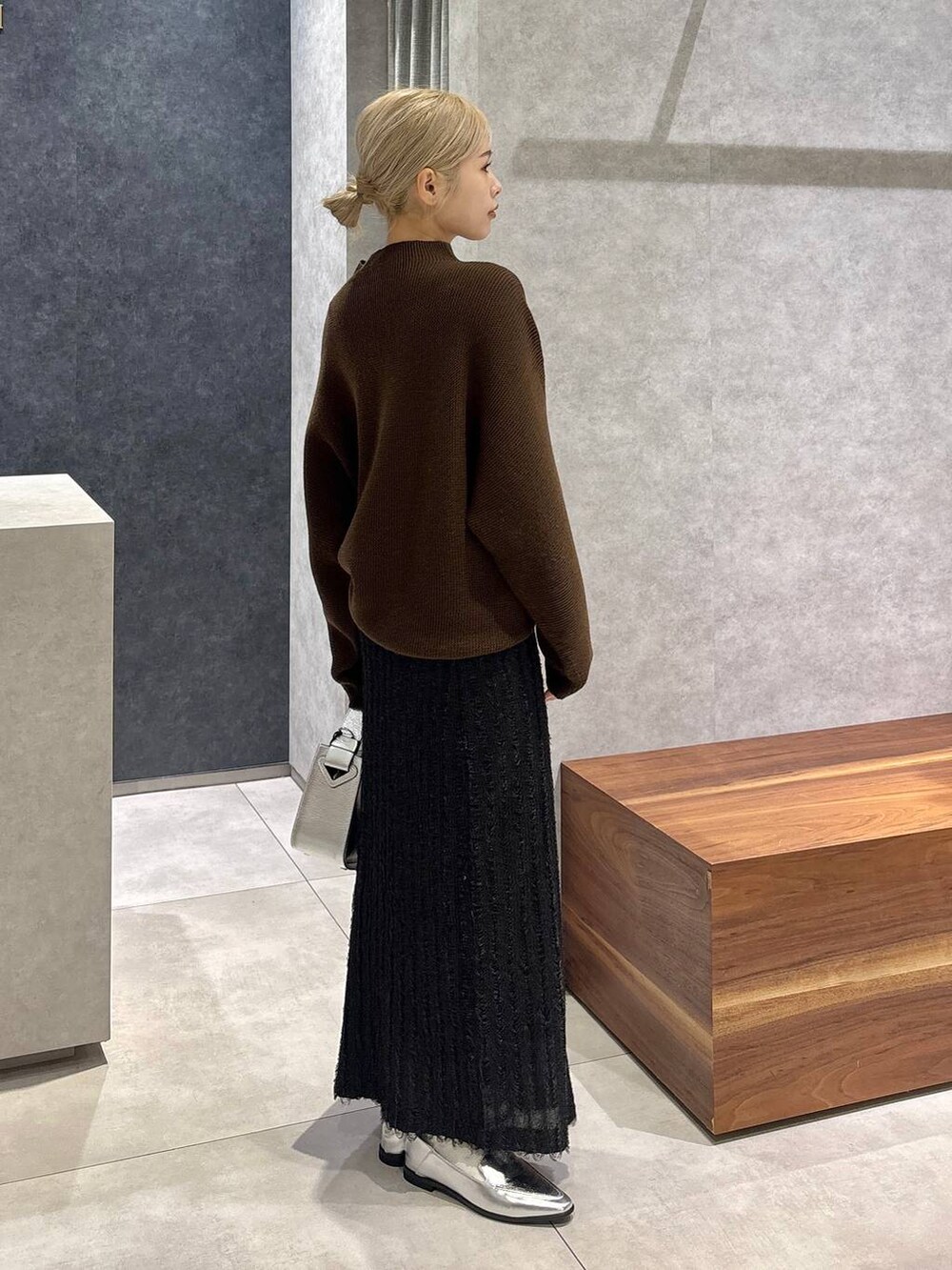 シルバー系のハンドバッグ、シルバー系のローファー、ブラック系のスカートを着用したレディースの冬コーディネートの2枚目の写真