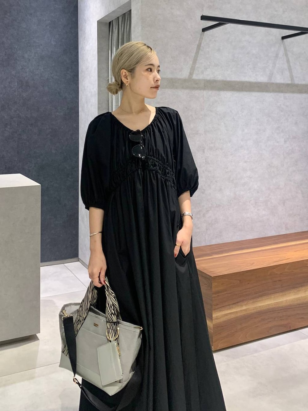 シルバー系のローファー、グレー系のトートバッグ、ブラック系のワンピースを着用したレディースの夏コーディネートの2枚目の写真