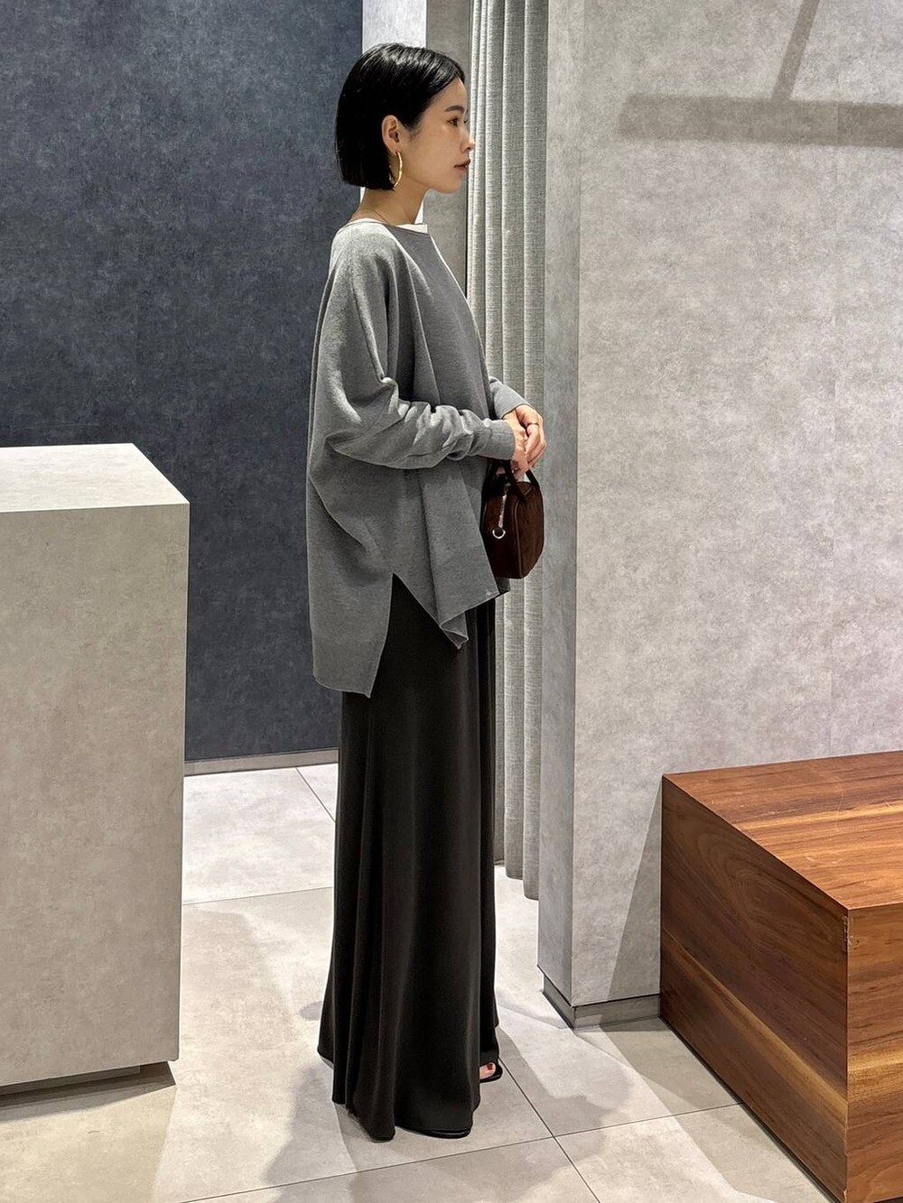 グリーン系のスカート、ホワイト系のTシャツ/カットソー、ブラウン系のショルダーバッグを着用したレディースの夏コーディネートの2枚目の写真