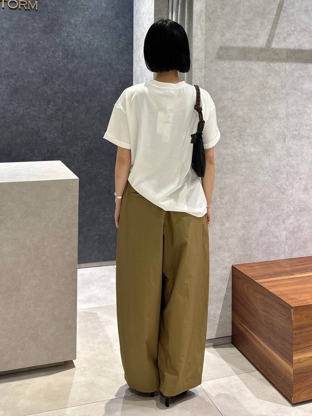 ベージュ系のその他パンツ、ブラック系のサンダル、ホワイト系のTシャツ/カットソーを着用したレディースの春コーディネートの4枚目の写真