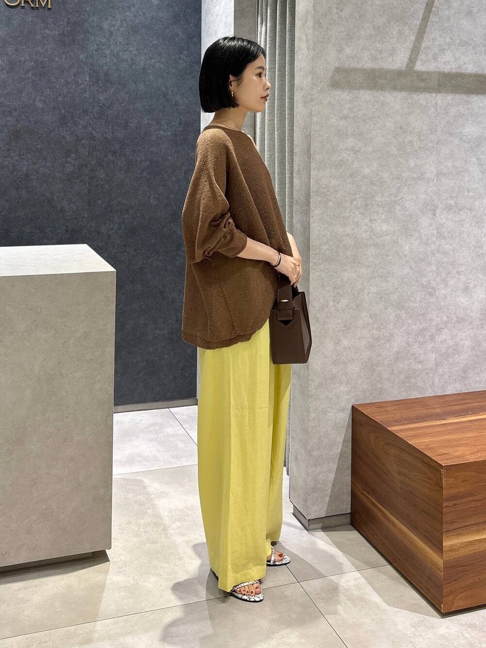 ブラウン系のハンドバッグ、ブラック系のキャミソール、ブラウン系のニット/セーターを着用したレディースの春コーディネートの2枚目の写真