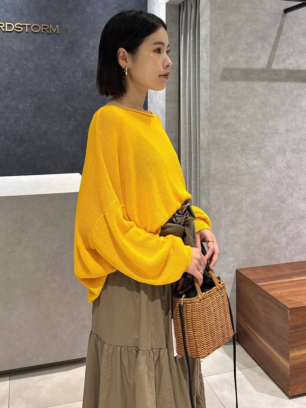 ブラック系のショルダーバッグ、ブラック系のサンダル、イエロー系のニット/セーターを着用したレディースの夏コーディネートの5枚目の写真