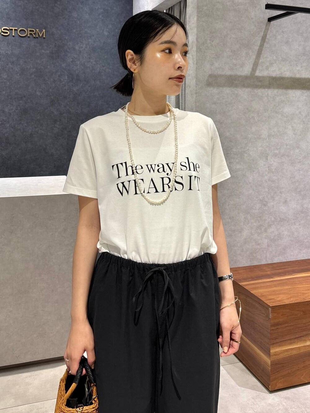 ブラック系のショルダーバッグ、ブラック系のサンダル、ホワイト系のTシャツ/カットソーを着用したレディースの夏コーディネートの4枚目の写真