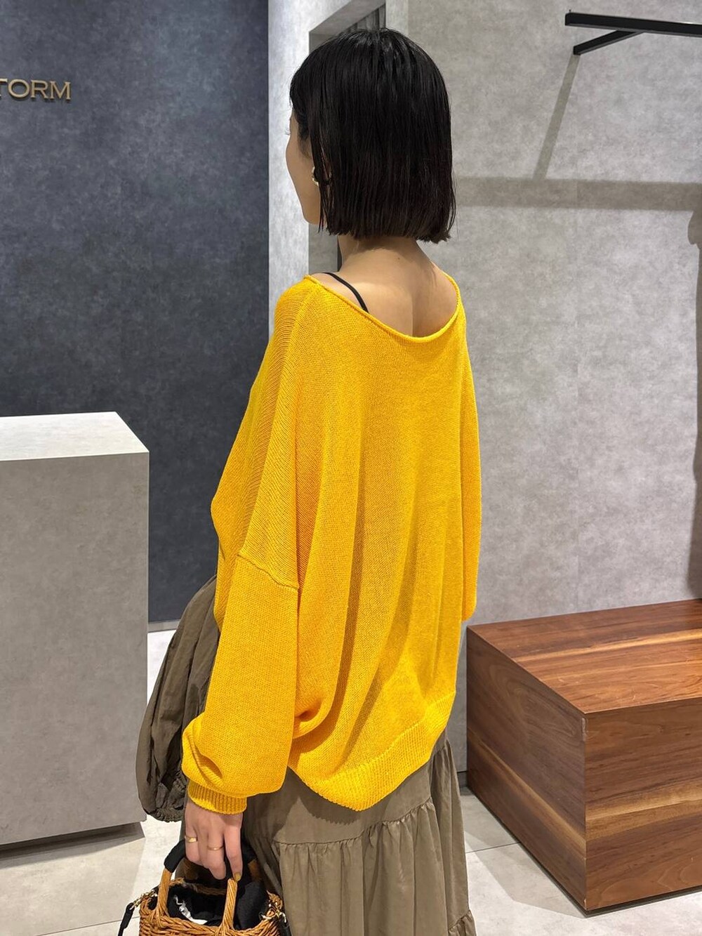 ブラック系のショルダーバッグ、ブラック系のサンダル、イエロー系のニット/セーターを着用したレディースの夏コーディネートの6枚目の写真