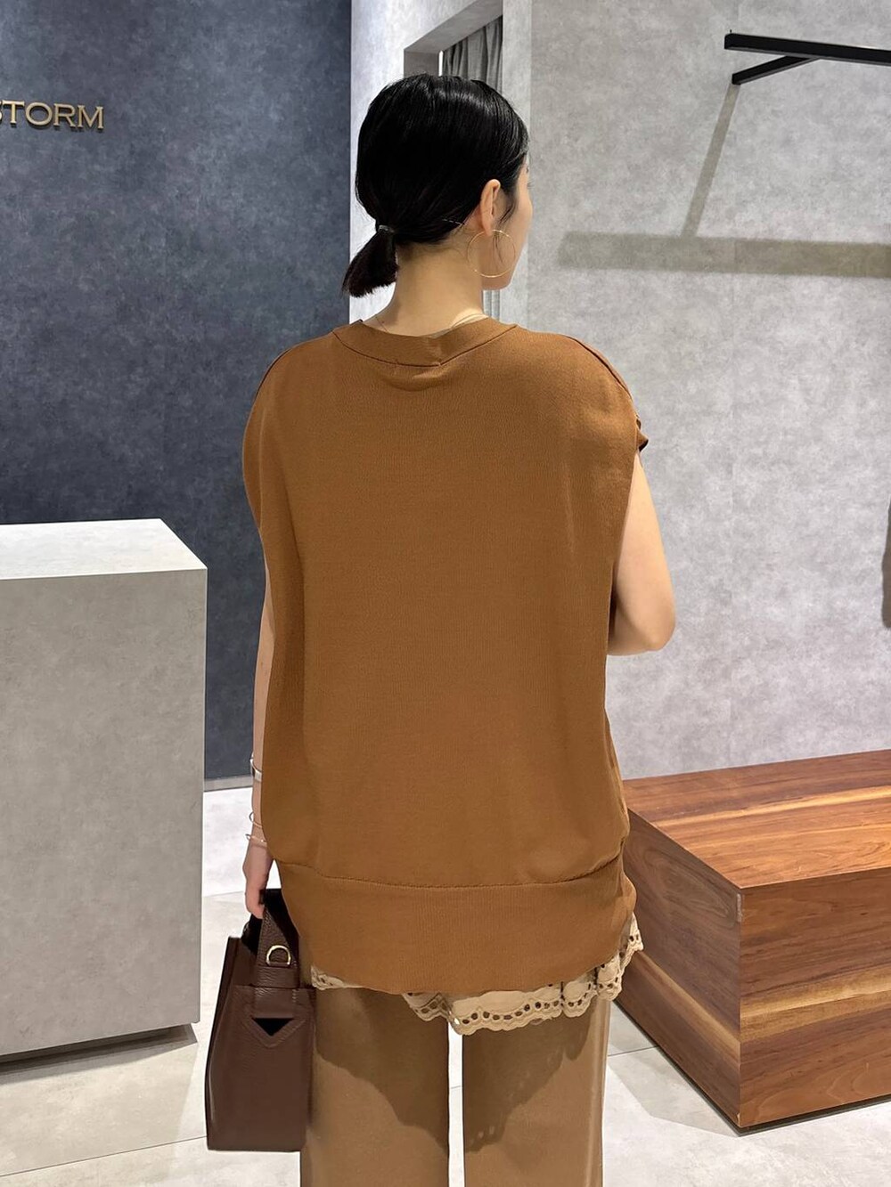 ブラウン系のハンドバッグ、ブラック系のサンダル、イエロー系のニット/セーターを着用したレディースの夏コーディネートの6枚目の写真