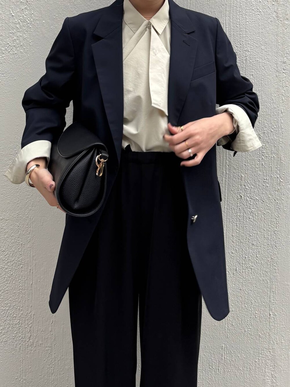 ブラック系のショルダーバッグ、ブラック系のスラックス、ブルー系のテーラードジャケットを着用したレディースの冬コーディネートの3枚目の写真