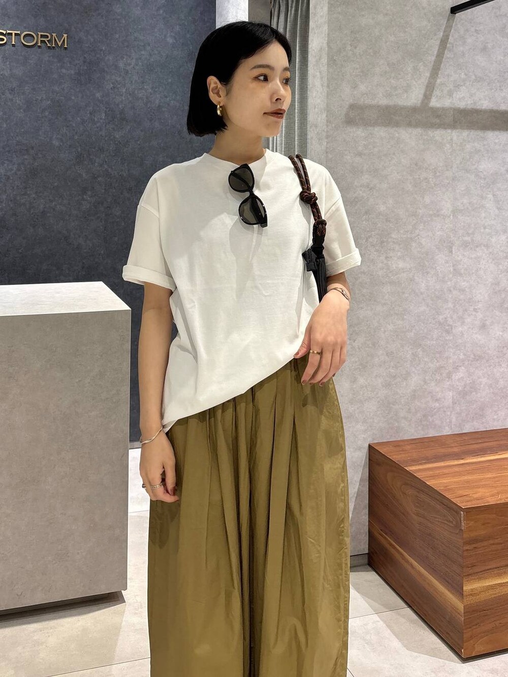 ベージュ系のその他パンツ、ブラック系のサンダル、ホワイト系のTシャツ/カットソーを着用したレディースの春コーディネートの6枚目の写真