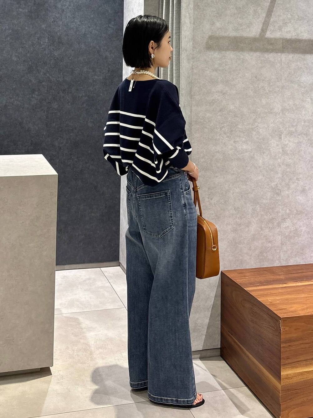 ブルー系のデニムパンツ、イエロー系のハンドバッグ、ブルー系のニット/セーターを着用したレディースの夏コーディネートの2枚目の写真