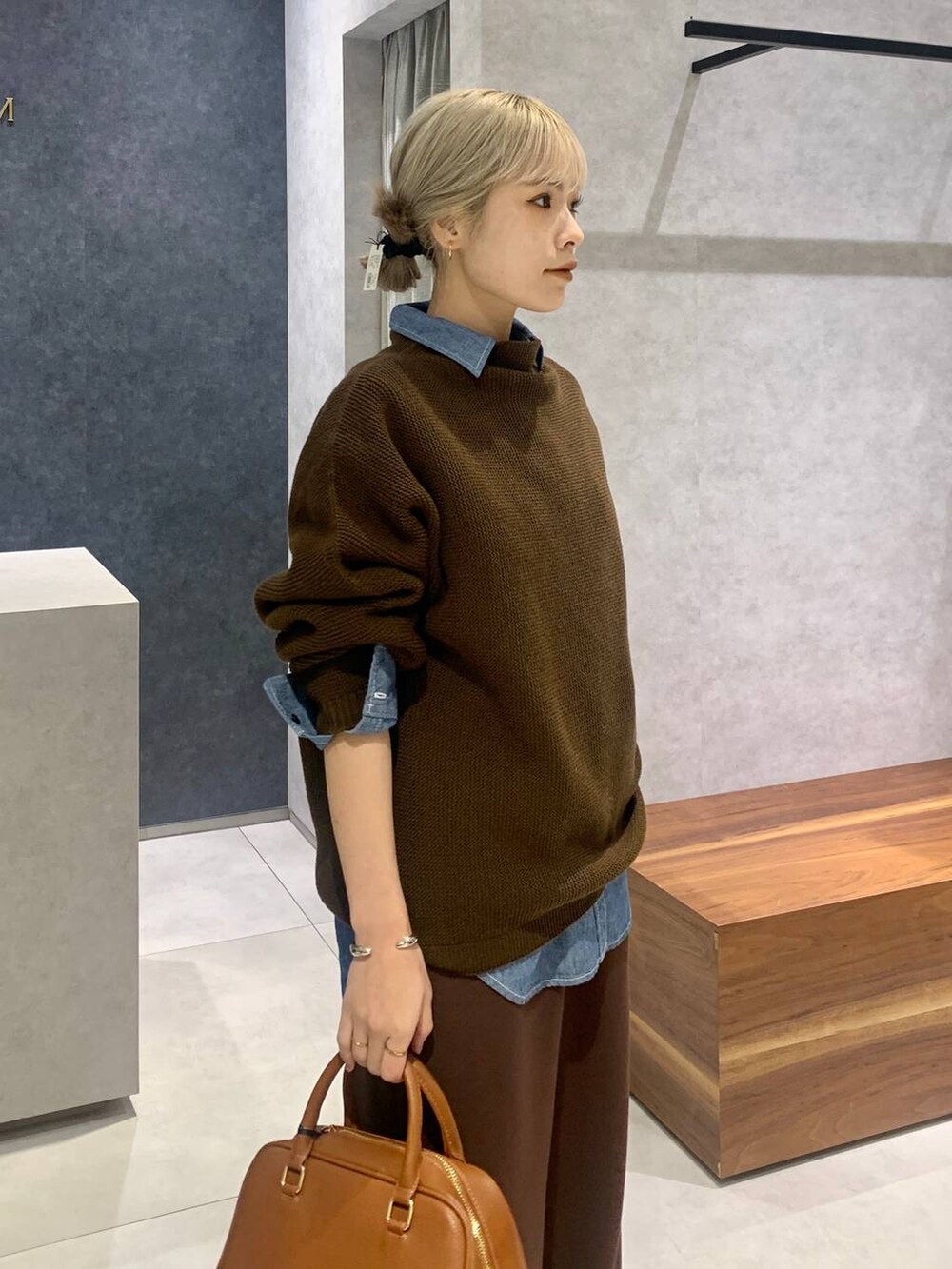 ブルー系のシャツ/ブラウス、イエロー系のボストンバッグ、ブラウン系のスウェットパンツを着用したレディースの冬コーディネートの3枚目の写真