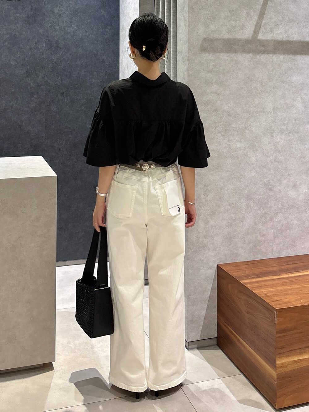 ホワイト系のデニムパンツ、ブラック系のサンダル、ブラック系のハンドバッグを着用したレディースの夏コーディネートの3枚目の写真
