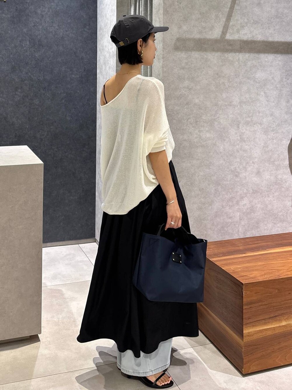 ブルー系のデニムパンツ、ブルー系のトートバッグ、ホワイト系のニット/セーターを着用したレディースの夏コーディネートの4枚目の写真