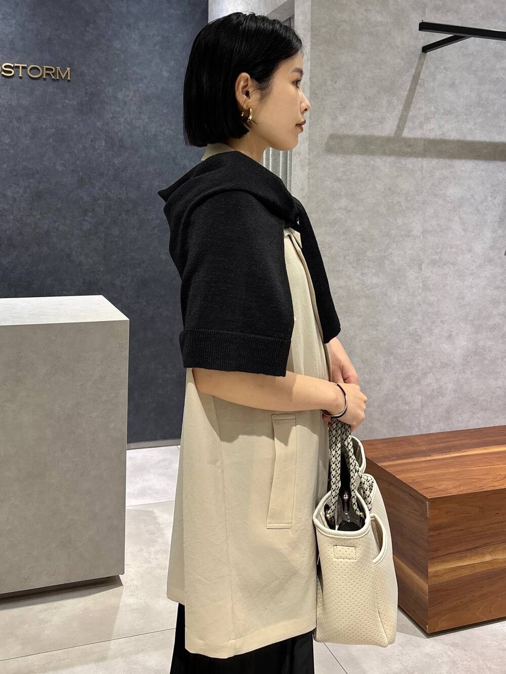 ブラック系のトートバッグ、ベージュ系のテーラードジャケット、ブラック系のサンダルを着用したレディースの春コーディネートの6枚目の写真