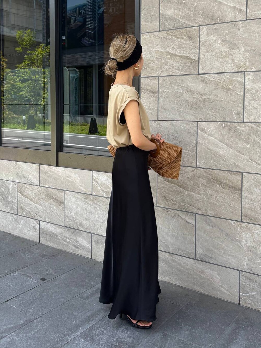 ブラウン系のトートバッグ、ベージュ系のTシャツ/カットソー、ブラック系のスカートを着用したレディースの春コーディネートの2枚目の写真