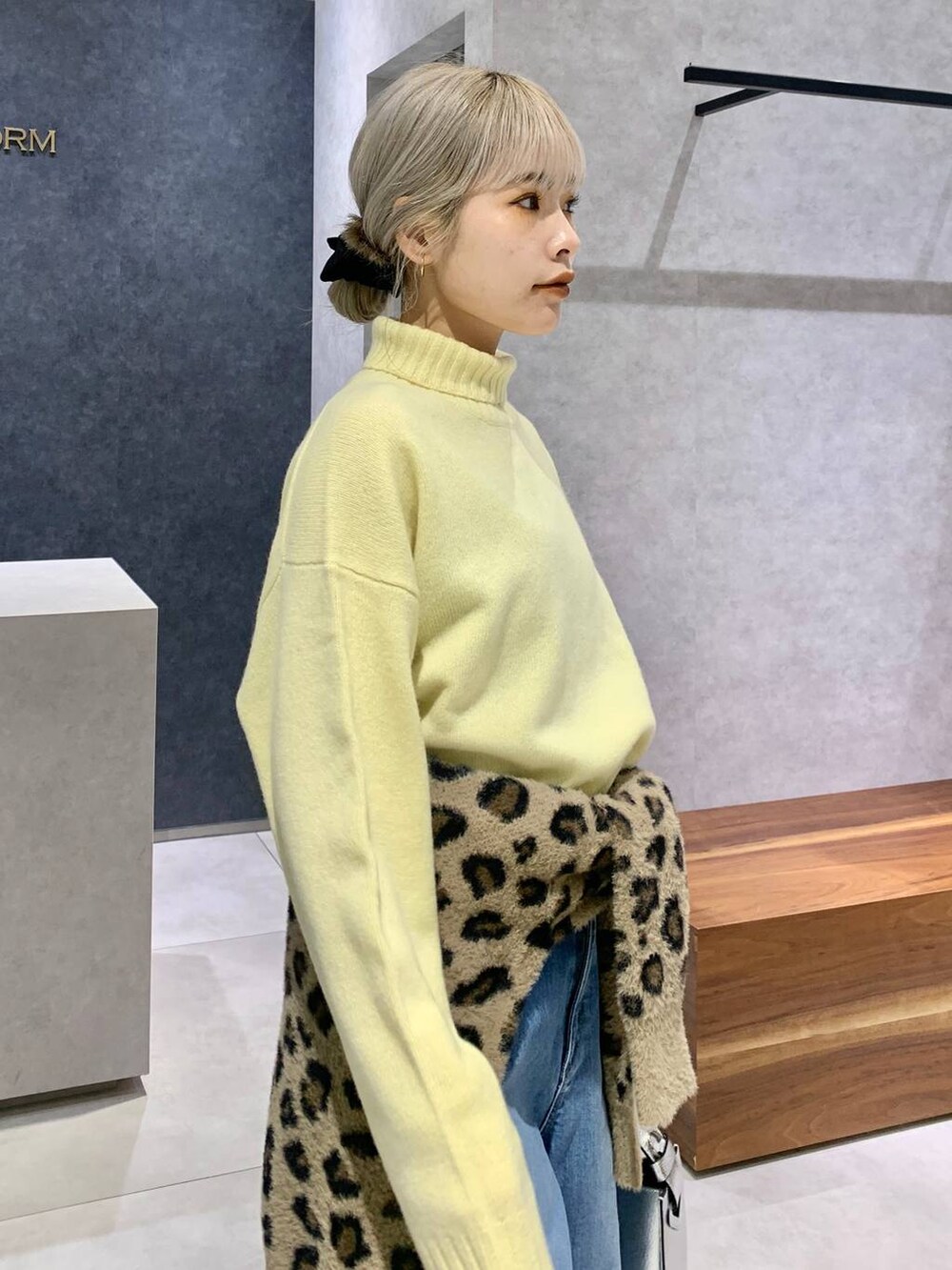 シルバー系のハンドバッグ、ブルー系のデニムパンツ、イエロー系のニット/セーターを着用したレディースの冬コーディネートの2枚目の写真